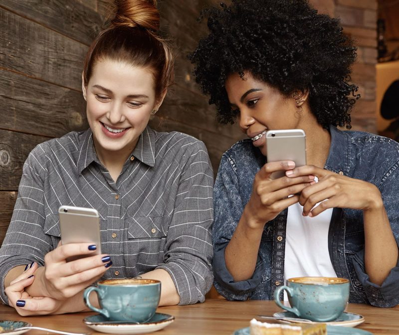 Friends at a coffee shop on their smartphones - PayPulse